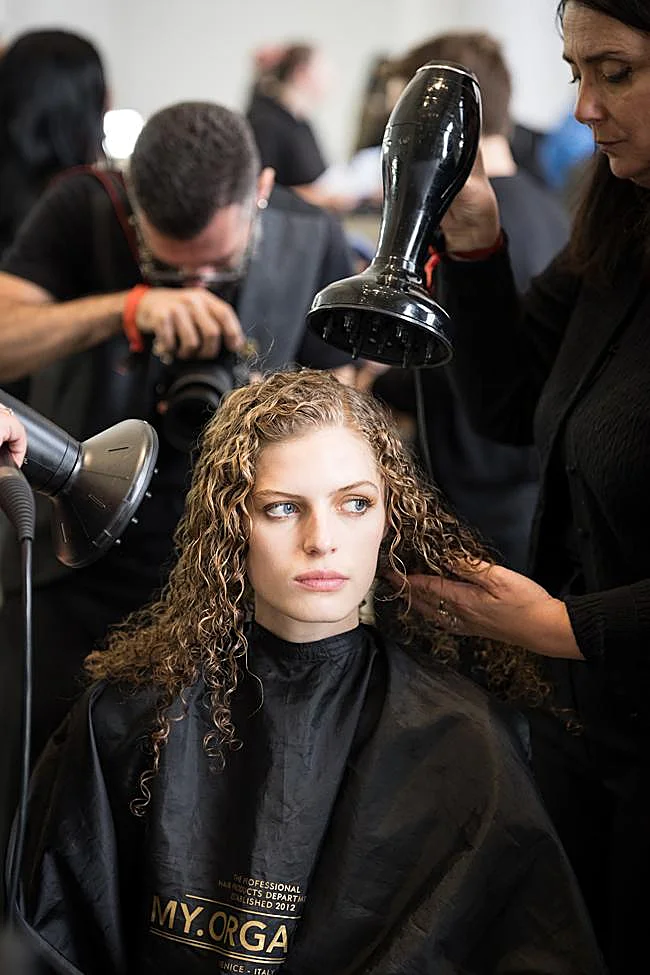 Un styliste séchant les cheveux d'un mannequin.